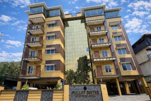 a tall yellow building with balconies on it at Pullat Suites in Kalpetta