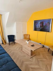 a living room with a tv on a yellow wall at Cosy travels in Les Andelys