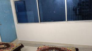 a room with two windows and two mats on the floor at Hotel Vasu in Gopālganj