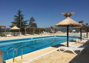 a swimming pool with chairs and umbrellas at DURANCE in La Brillanne