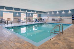 een groot zwembad met tafels en stoelen in een gebouw bij Holiday Inn Express Hotel & Suites Bismarck, an IHG Hotel in Bismarck