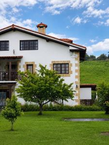 a white house with a tree in the yard at Posada Adela in Santillana del Mar