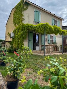 a house covered in ivy with a table and chairs at appartement avec piscine commune le chêne blc in Gargas