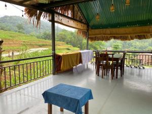 a room with a table and chairs on a balcony at Ha Giang Uphill Coffee Farmstay in Ha Giang