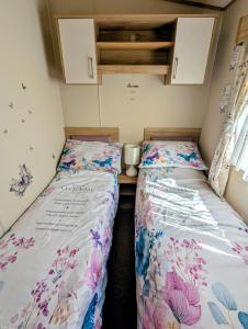 two beds in a small room with flowers on them at Island Butterfly haven in Sandown +9 photos