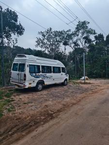 a white bus parked on the side of a dirt road at Periyarhills 2 BHK Budget villa Thekkady in Thekkady