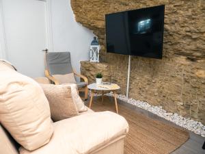 a living room with a couch and a tv on a stone wall at Casa isabel in Setenil