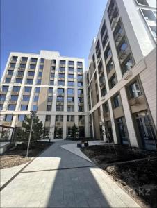a large white building with a sidewalk in front of it at Designer Apartment with Mountain View in Almaty