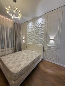 a bedroom with a bed and a chandelier at Designer Apartment with Mountain View in Almaty