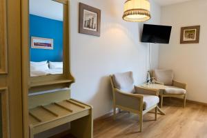 a room with a mirror and a bed and a chair at Hotel Heidenauer Hof in Heidenau