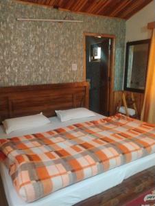 a bedroom with a bed with a plaid blanket at Shivpur Greens in Mashobra