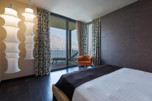 a bedroom with a bed and a chair and a window at Piccolo Hotel in Malcesine