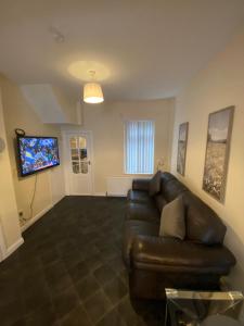 a living room with a leather couch and a flat screen tv at spamount house in Belfast