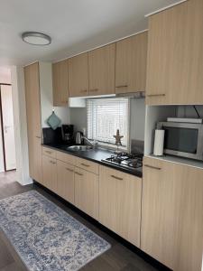 eine Küche mit Holzschränken, Spüle und Mikrowelle in der Unterkunft J 187 in Petten