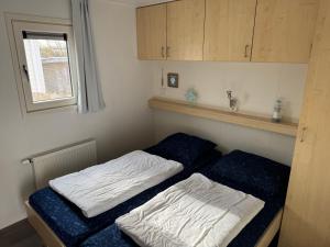 ein Schlafzimmer mit einem Bett mit zwei weißen Laken in der Unterkunft J 187 in Petten