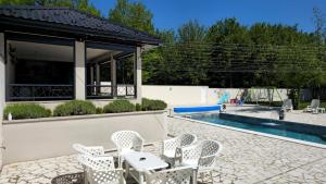 a patio with white chairs and a swimming pool at Villa Aida in Sarajevo