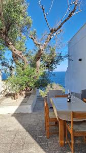 a wooden table and chairs with a view of the ocean at A-mare Casa vacanza in Gagliano del Capo
