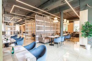 a restaurant with white tables and blue chairs at AYKUN Hotel in Almaty