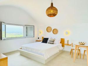 a white bedroom with a bed and a table at Nohēme Luxury Suites in Vourvoúlos +90 photos