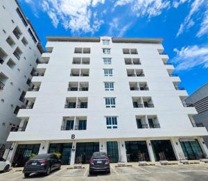 a white building with cars parked in front of it at PKK hotel Residence in Bang Phli