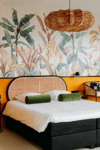 a bed with two green pillows in a room with a floral wall at La Paulowna Boutique Hotel in The Hague