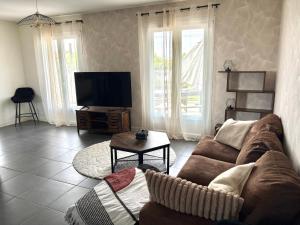 a living room with a couch and a flat screen tv at Maison Salignac 9 personnes in Salignac Eyvigues
