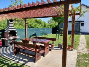 a wooden pergola with a picnic bench and a grill at kuća za odmor Domus Alba in Branjin Vrh