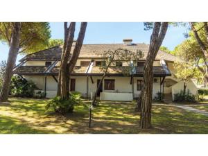 a house with a group of trees in front of it at Sotto il Pino 14 in Eraclea Mare