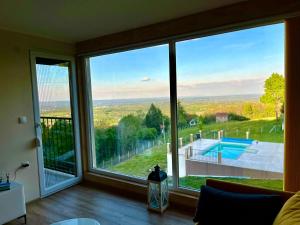 a living room with a large window looking out at a pool at Imanje POGLED in Arandelovac