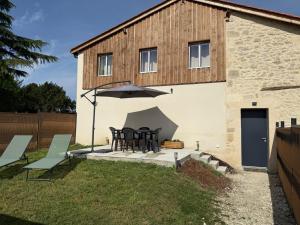 a patio with a table and an umbrella in front of a building at ô Vignes & Bastides " L'échappée Lapébie ", appartement cosy in Sauveterre-de-Guyenne