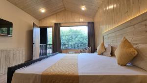 a bedroom with a large bed with a large window at Aqua Forest River Resort in Bijni +135 photos