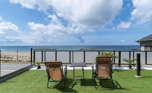 two chairs and a table on a balcony with the beach at Tabinoteitaku Y-beach in Tsuruoka