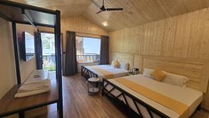 a bedroom with two beds and a balcony at Aqua Forest River Resort in Bijni