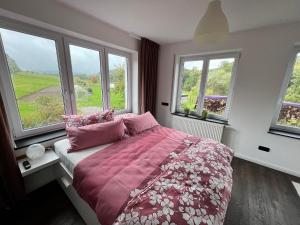 a bedroom with a bed with pink sheets and windows at Ferienwohnung Rhön Natur in Hilders