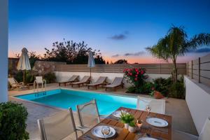 a patio with a table and chairs and a swimming pool at Gemini Villas in Theologos