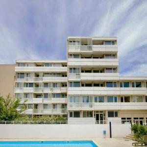 an apartment building with a pool in front of it at Hôtel Residence Les Aiguades in Port-de-Bouc