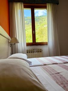 a bedroom with a bed and a window with a view at Hotel Mezzolago in Calceranica al Lago
