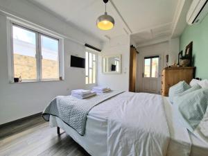 a bedroom with a white bed and two windows at Xenia Studios in Piskokéfalon