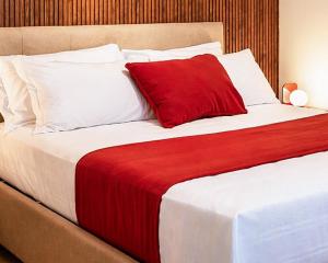a large bed with a red pillow on it at N'Ador Rooms in Naples