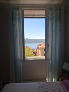a bedroom window with a view of the ocean at Casa Azzurra in Portoferraio +3 photos