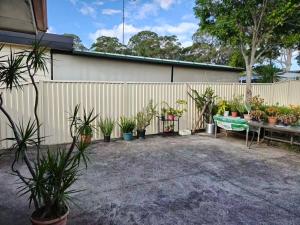 a fence with a bunch of potted plants and a bench at Bright Double Room N Winston Hills in Toongabbie
