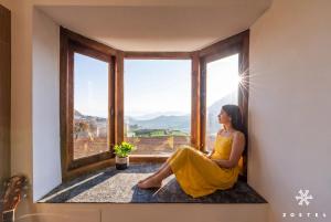 a woman in a yellow dress sitting in a window at Zostel Ooty, Pudumund in Ooty