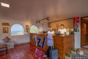 a man and a woman standing at a counter with a laptop at Zostel Ooty, Pudumund in Ooty
