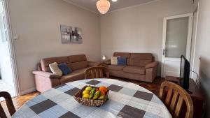 a living room with a table with a bowl of fruit at Gloria's House in Lagoa