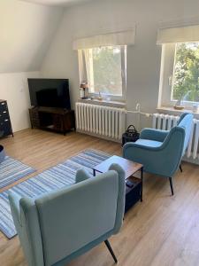 a living room with blue chairs and a tv at Das Gardenhouse - Hohensee in Zemitz