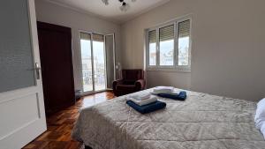 a bedroom with a bed with two towels and a chair at Gloria's House in Lagoa