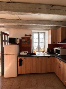 a kitchen with wooden cabinets and a white refrigerator at Maison Lilas in Pontarion