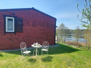 two chairs and a table in front of a red building at Domus Mare Tiny House 1 in Wisełka