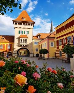 a building with a tower in a courtyard with flowers at Rohonci Vendégház in Kőszeg