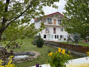 a white house with a pond in the yard at La Bica in Bîrnova